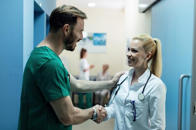 Cirujano feliz y doctora saludando en un pasillo de la clínica El foco está en la doctora