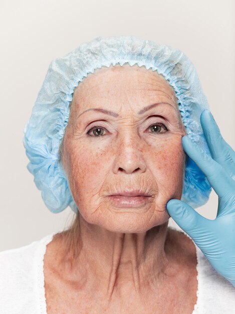 Cirujano haciendo chequeo de piel en mujer de mediana edad antes de la cirugía plástica