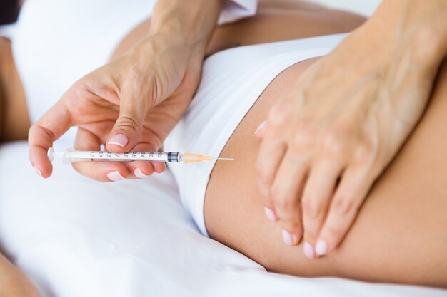 Cirujano que hace la inyección en el cuerpo femenino. Concepto de liposucción