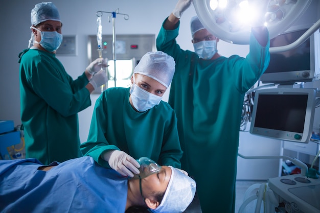 Cirujanos que ajustan la máscara de oxígeno en la boca del paciente en quirófano