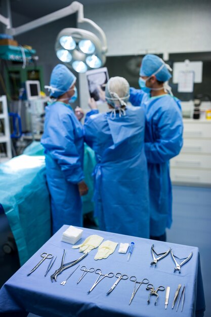 Los cirujanos que discuten en la radiografía paciente en la sala de operación