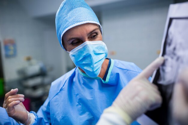 Los cirujanos que discuten en la radiografía paciente en la sala de operación