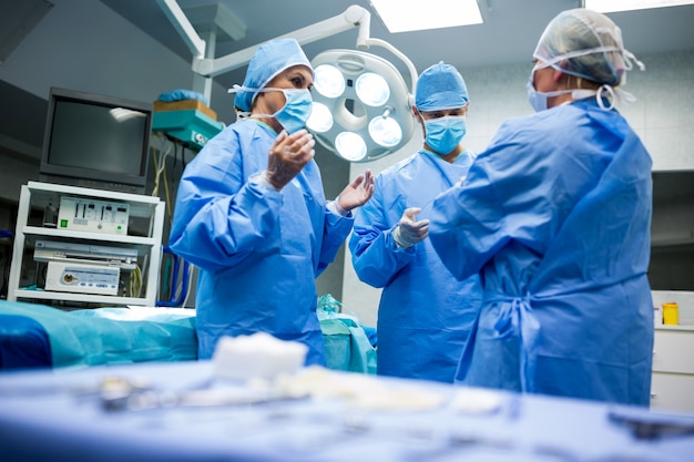 Foto gratuita los cirujanos que interactúan entre sí en la sala de operación