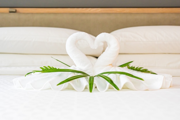 Cisne de toalla blanca en la decoración de la cama interior del dormitorio