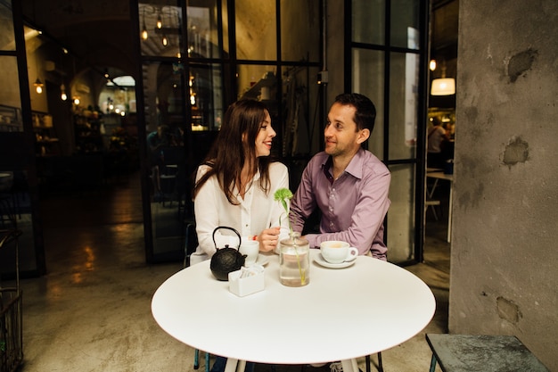 Cita romántica. Feliz pareja de enamorados en café en su fecha mirando el uno al otro y sonriendo