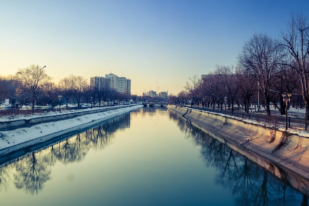 Ciudad con río y planta de energía fumando en el fondo