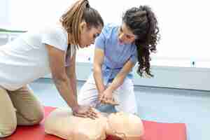 Foto gratuita clase de rcp con instructores hablando y demostrando compresiones de primeros auxilios y procedimiento de reanimación maniquí de rcp