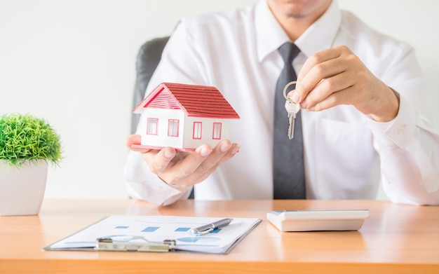 Foto gratuita clave de la casa en la protección de manos del agente de corredores de seguros del hogar