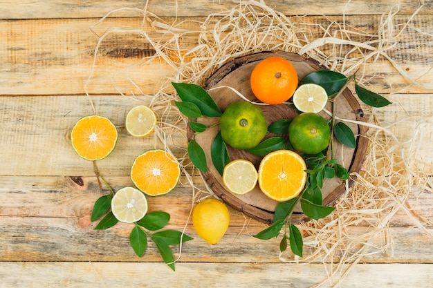 Clementinas de primer plano sobre tablero de madera con limas y mandarinas sobre tablero de madera