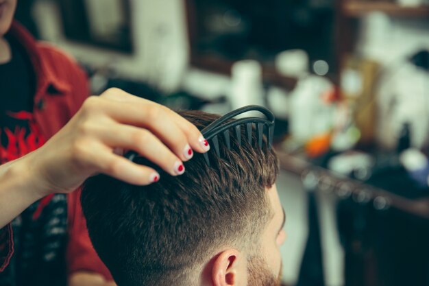 Cliente durante el afeitado de barba en peluquería. Peluquería femenina en el salón. Igualdad de género. Mujer en la profesión masculina. Manos cerca