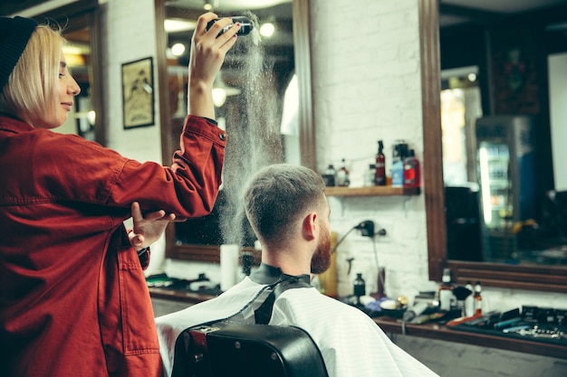 Cliente durante el afeitado de barba en peluquería. Peluquería femenina en el salón. Igualdad de género. Mujer en la profesión masculina.