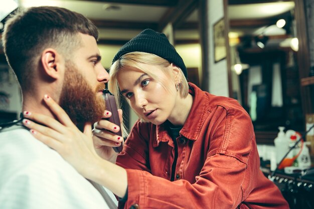 Cliente durante el afeitado de barba en peluquería. Peluquería femenina en el salón. Igualdad de género