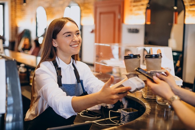 Cliente comprando café en una cafetería y pagando con tarjeta