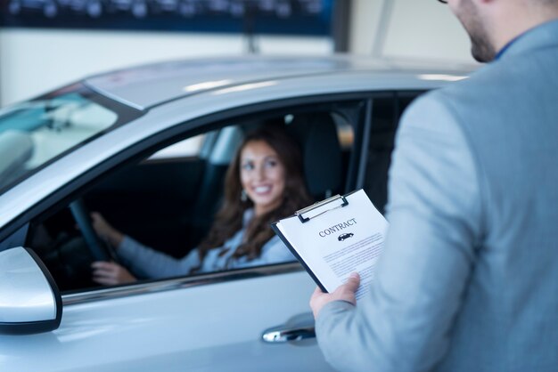 Cliente feliz comprando un coche nuevo en el concesionario de vehículos