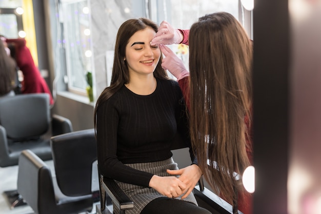 El cliente feliz está esperando el resultado final del maquillaje de la noche