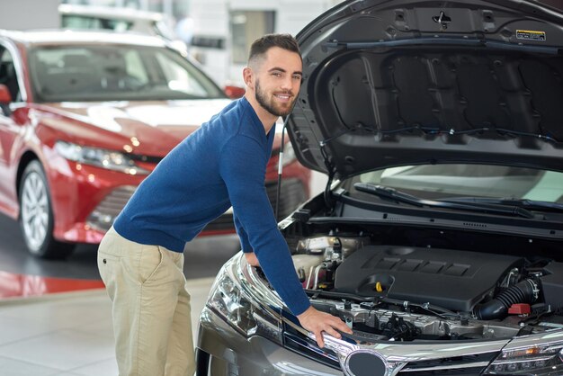 Cliente feliz revisando el auto en el salón de autos antes de comprarlo