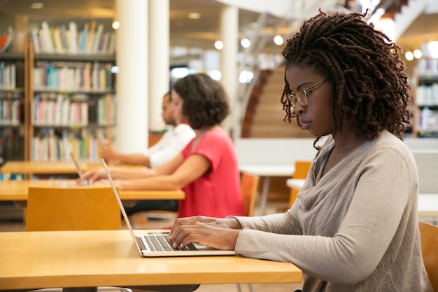 Cliente femenino enfocado que usa el punto de acceso público wi-fi en la biblioteca