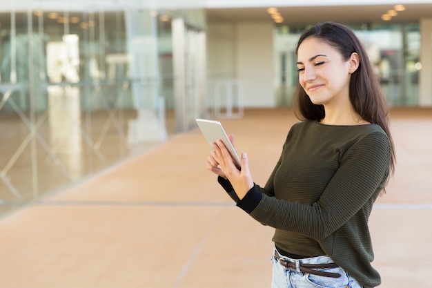 Cliente femenino satisfecho feliz que controla el correo electrónico en la tableta