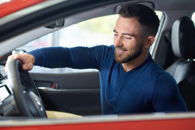 Cliente joven que viene al salón del automóvil y quiere comprar un automóvil