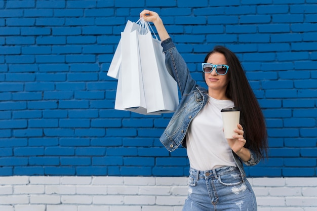 Cliente joven sosteniendo bolsas de compras y café