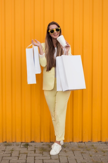 Foto gratuita cliente joven vistiendo ropa amarilla con bono y bolsas