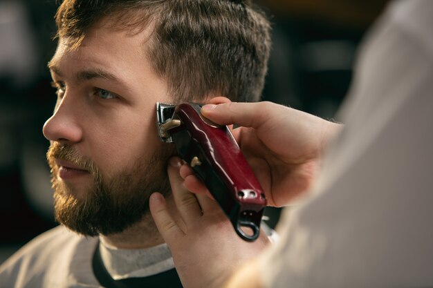 cliente del maestro barbero, estilista durante la atención y un nuevo aspecto de peinado