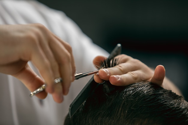 Cliente del maestro barbero, estilista durante la atención y un nuevo aspecto de peinado