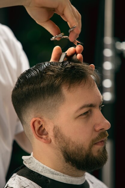 cliente del maestro barbero, estilista durante la atención y un nuevo aspecto de peinado