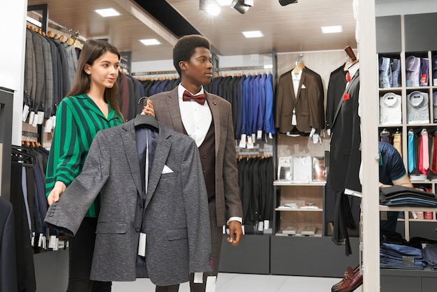 Cliente masculino elegir elegante traje en la tienda.