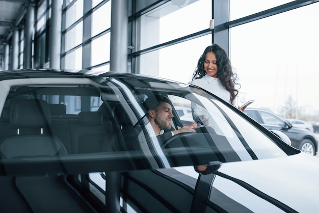 Cliente masculino y empresaria moderna en el salón del automóvil