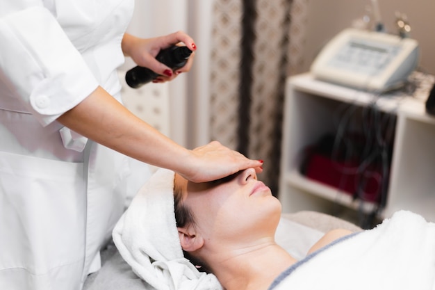 Foto gratuita cliente mujer en salón recibiendo masaje facial manual de esteticista