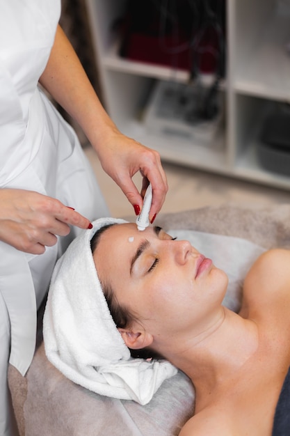 Cliente mujer en salón recibiendo masaje facial manual de esteticista