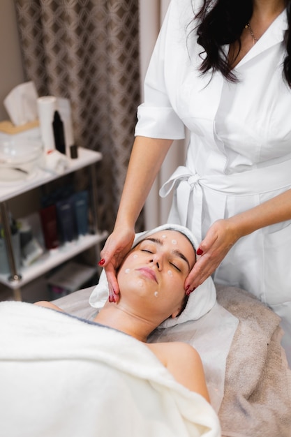 Cliente mujer en salón recibiendo masaje facial manual de esteticista