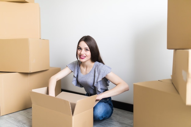 El cliente sonriente satisfecho de la mujer joven se sienta en el sofá desempaque el paquete abierto el paquete, el consumidor feliz de la muchacha que sostiene la caja de cartón recibe una buena compra de la tienda en línea en casa, el concepto de entrega de envío por correo