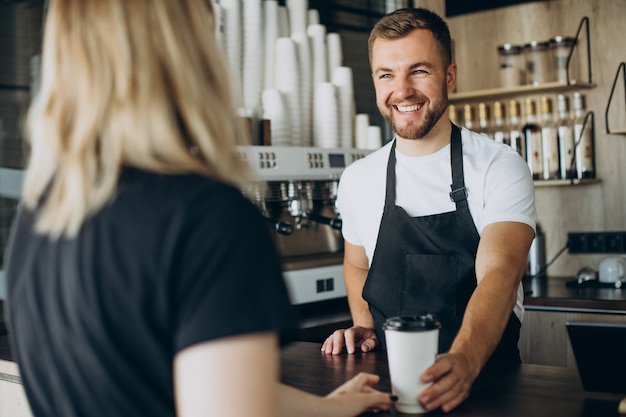 Cliente surving barista con café en una cafetería.