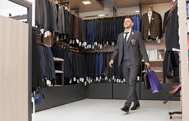 Cliente en traje en boutique con bolsas de compras.