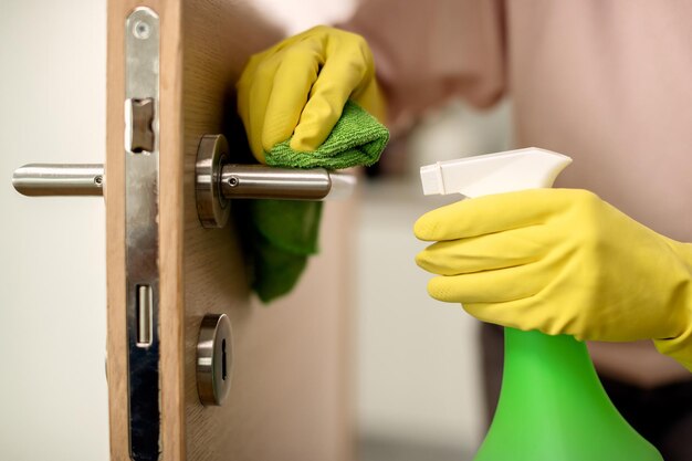 Cloeup de mujer desinfectando la manija de la puerta en casa