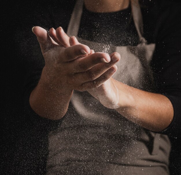 Close-up baker limpiando las manos de harina