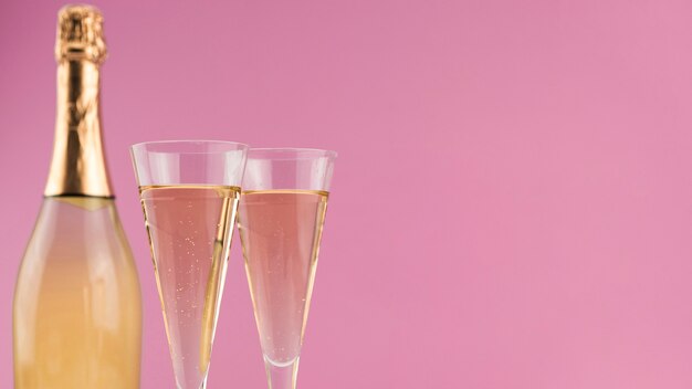 Close-up de botella de champagne con copas y espacio de copia