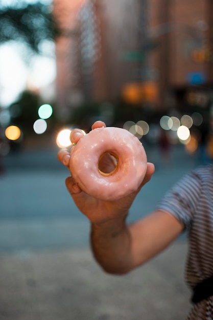 Close-up boy sosteniendo una rosquilla glaseada