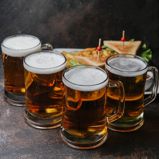 Close-up cerveza con un plato de sándwich y papas fritas