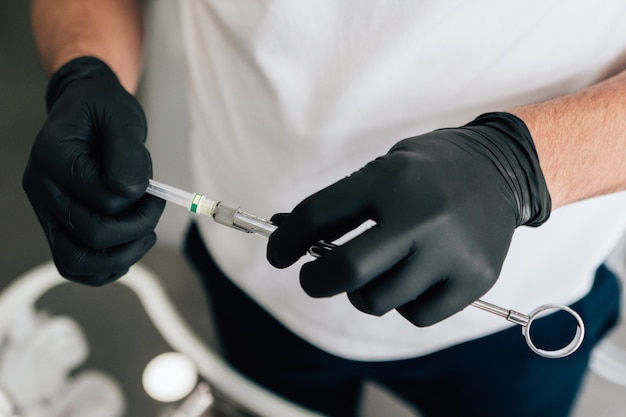 Close-up de dentista con equipo con guantes quirúrgicos