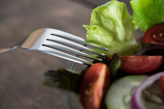 Close up de ensalada de verduras frescas en el recipiente con fondo de madera rústica de edad. Concepto de alimentos saludables.