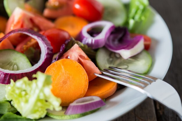 Close up de ensalada de verduras frescas en el recipiente con fondo de madera rústica de edad. Concepto de alimentos saludables.