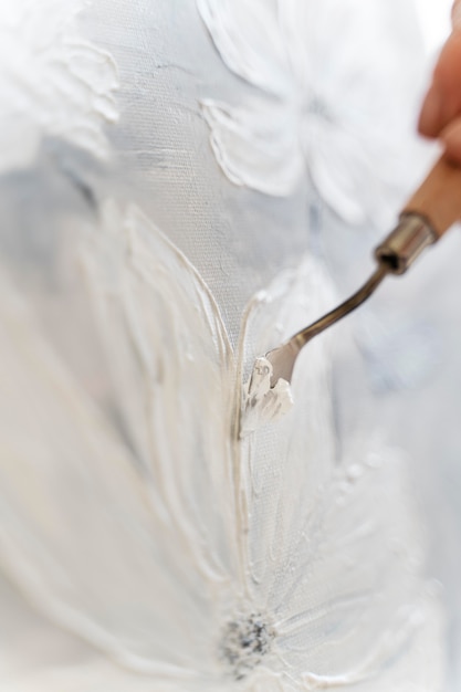 Close-up de espátula de pintura con lienzo y flor