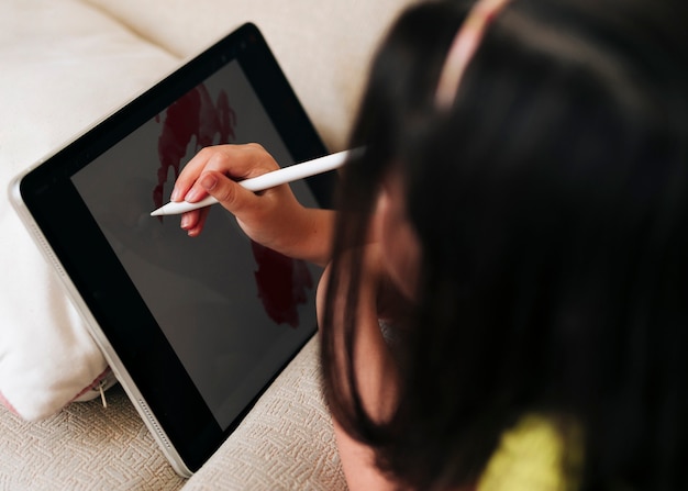 Close-up girl dibujo en su tableta con bolígrafo