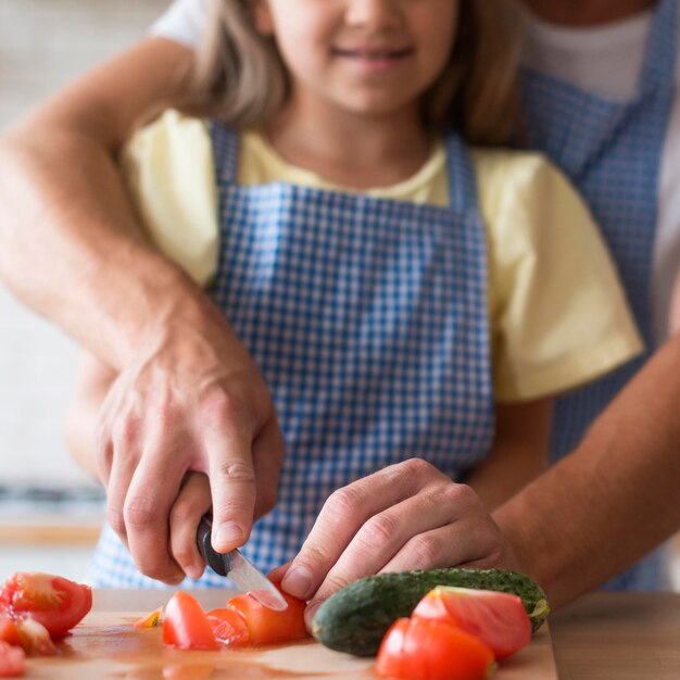 Close-up girl y papá cortando tomate