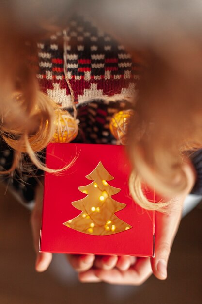 Close-up girl con regalo y luces de navidad