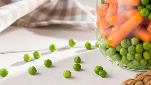 Close-up de guisantes en escabeche y zanahorias pequeñas en frascos