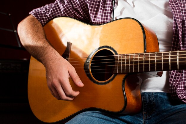 Close-up guitarra acústica y chico sentado